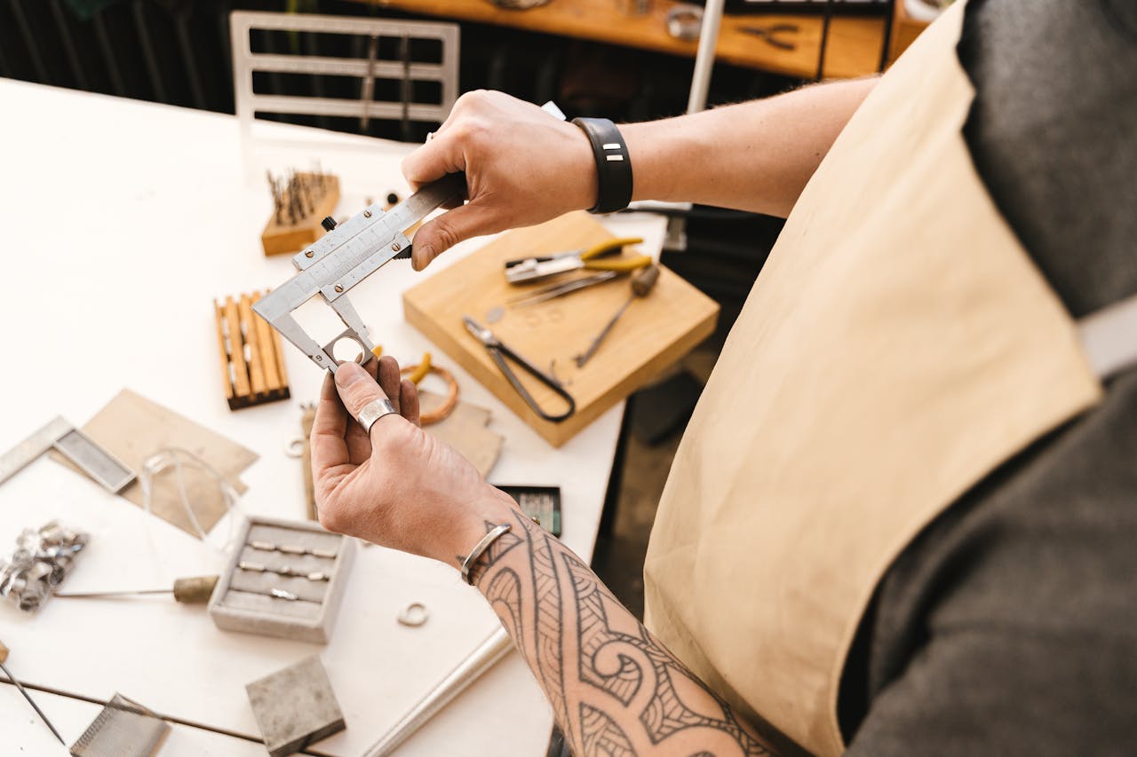 Close-up of artisan using a vernier caliper to measure metal in a workshop setting.